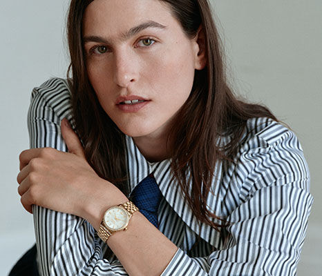 Woman in a striped shirt wearing a gold Vivienne Westwood watch.